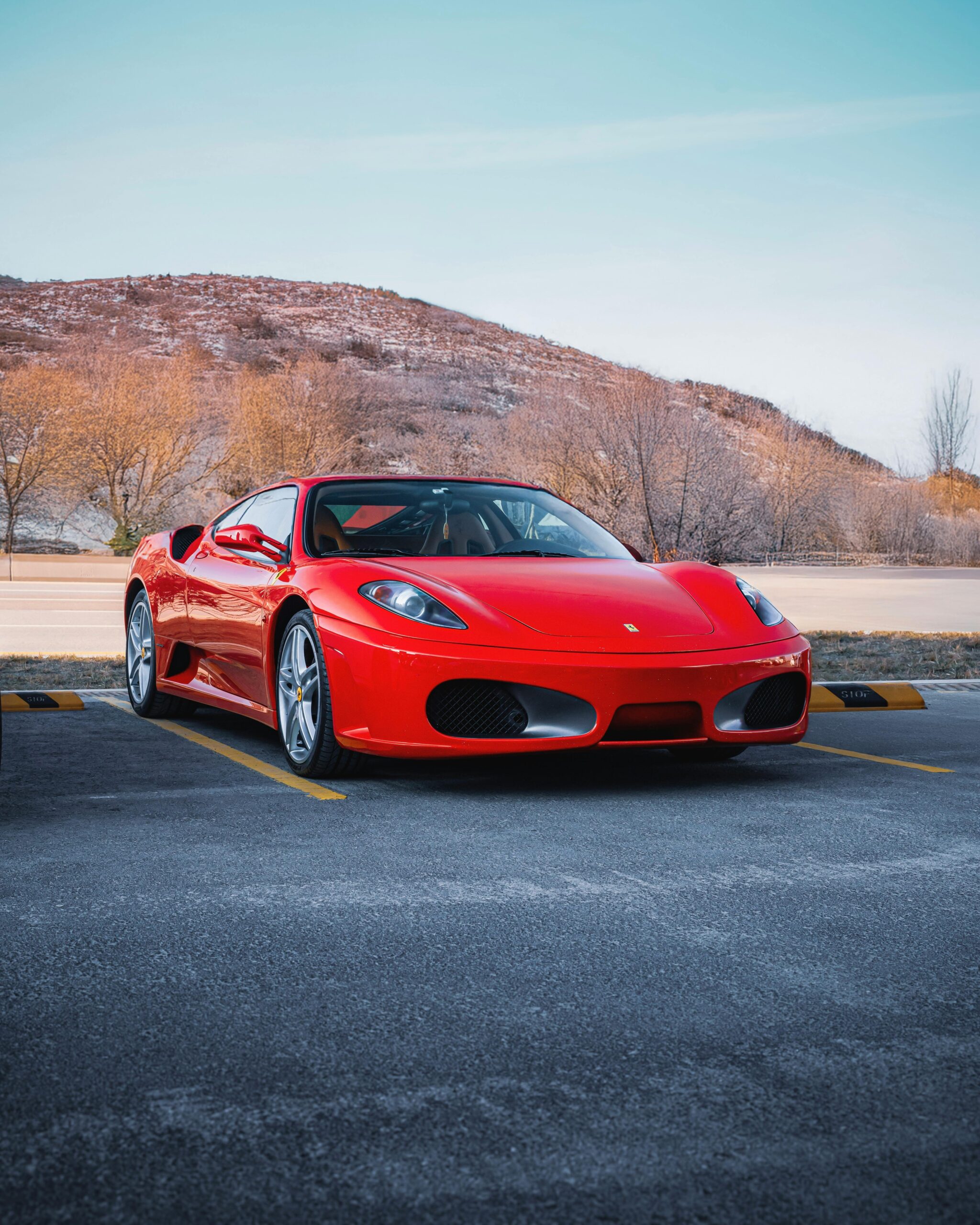 A stunning red Ferrari car parked against a scenic Ankara backdrop, showcasing luxury and style.